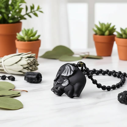 Black elephant pendant with white details on a blurred floral background