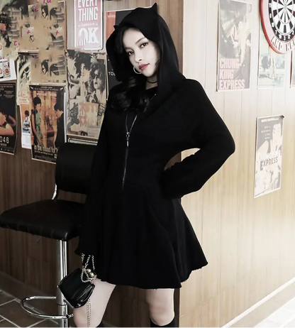 Person wearing a black hoodie and skirt in a room with posters on the wall.