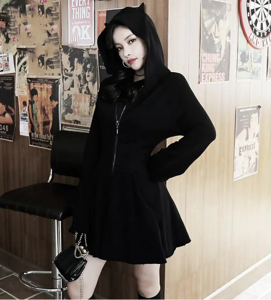 Person wearing a black hoodie and skirt in a room with posters on the wall.