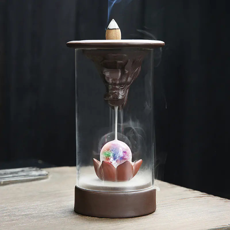 Incense burner with a colorful crystal ball inside on a wooden surface.