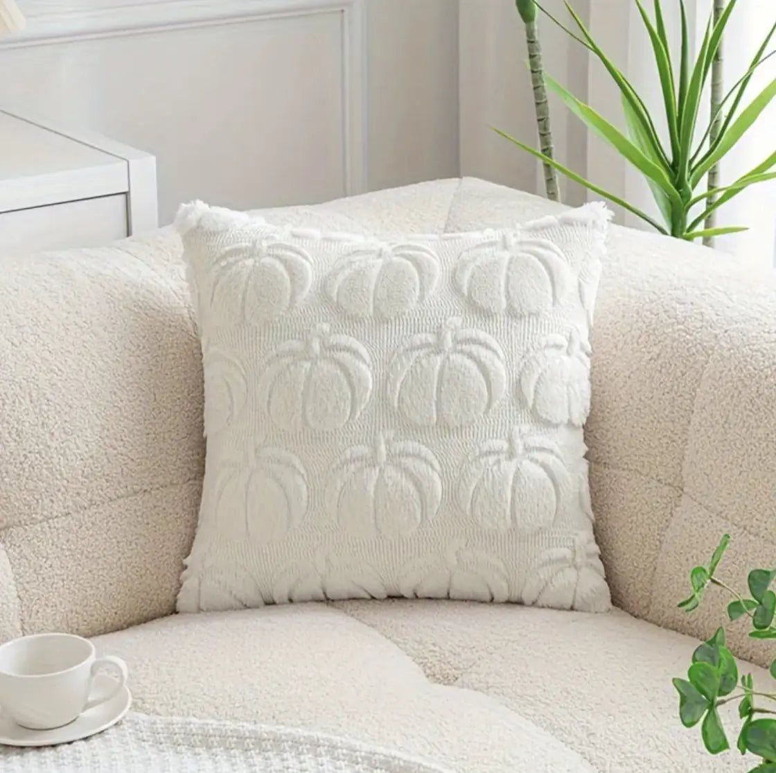 White textured pillow on a beige sofa with a cup and plant in the background