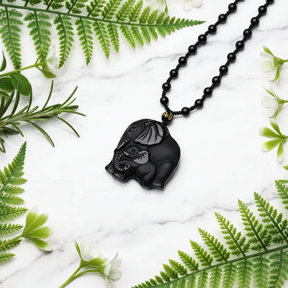 Black elephant pendant on a beaded necklace with a blurred floral background