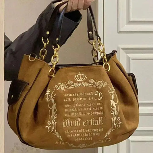 Brown handbag with gold embossed text held by a person indoors.