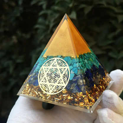 Pyramid-shaped crystal with geometric design held by a gloved hand against a dark background