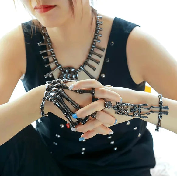 Person wearing black skeleton-themed jewelry including a necklace, bracelet, and ring.