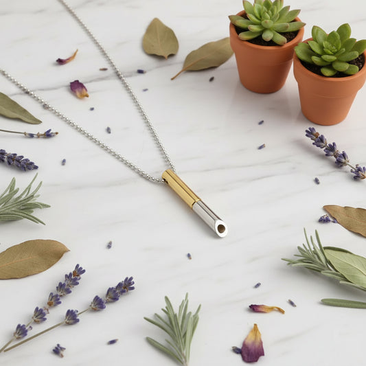 Necklace with a gold and silver cylindrical pendant on a white background