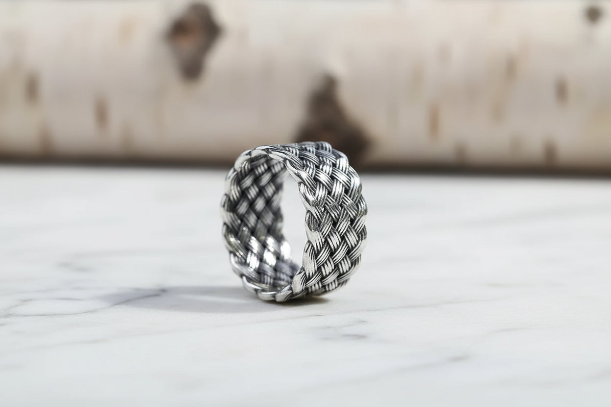 Silver woven ring on a wooden surface with a blurred background