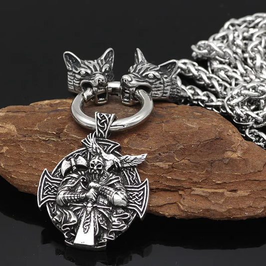 Silver pendant with wolf heads on a chain, placed on a wooden surface.