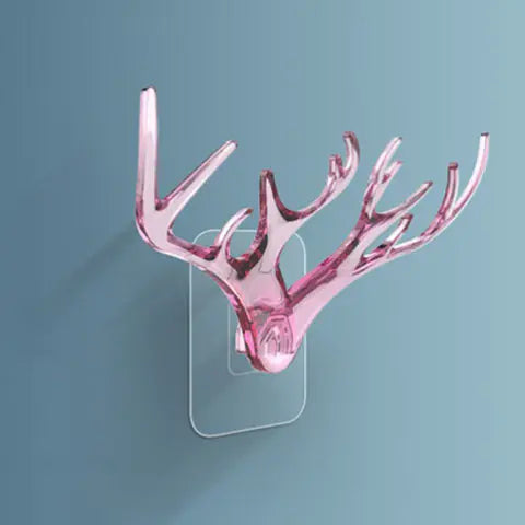 Pink antler-shaped wall hook on a clear stand against a blue background