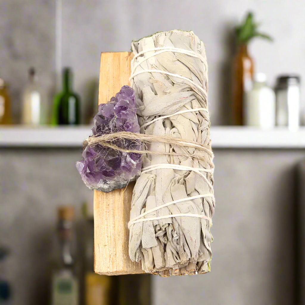 Sage bundle, amethyst crystal, and Palo Santo on a white background