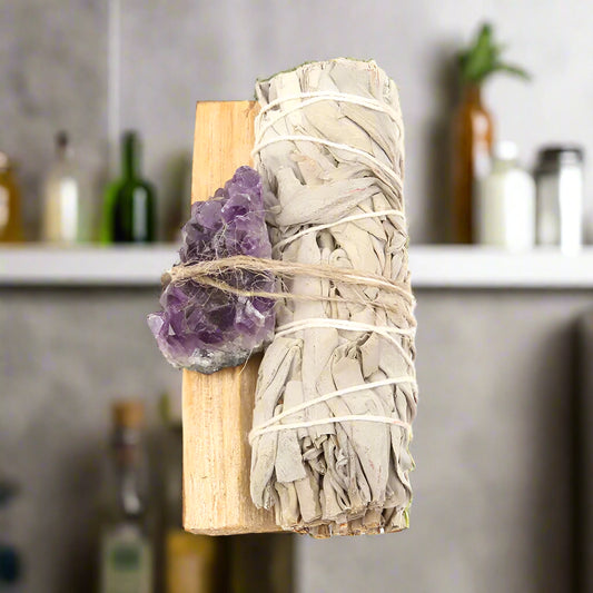 Sage bundle, amethyst crystal, and Palo Santo on a white background