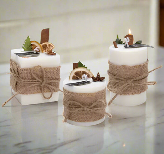 Set of three candles wrapped in burlap with decorative elements on a white background