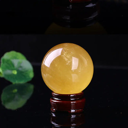 Yellow crystal ball on a dark background with a green leaf