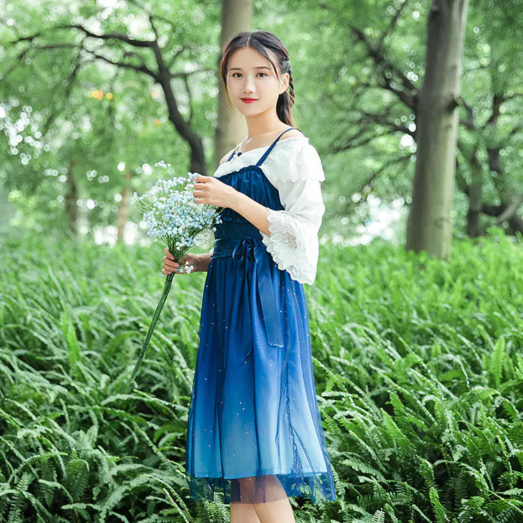 Woman in a blue dress holding flowers in a green forest