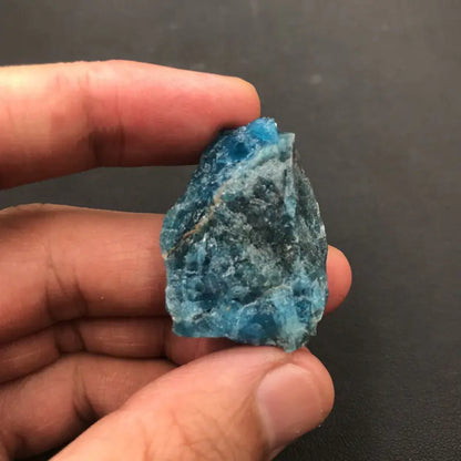 Hand holding a blue crystal against a dark background