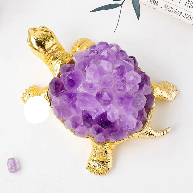 Gold turtle pendant with purple crystal on a white background
