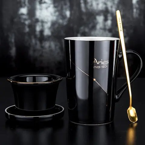 Black mug with 'Aries' text, gold spoon, and black filter basket on a dark background