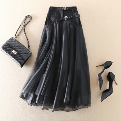 Black skirt with belt, black quilted handbag, and black high heels on a beige background