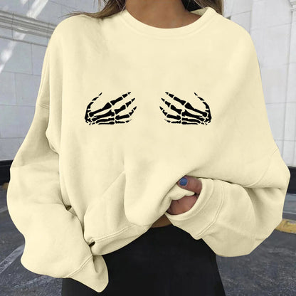 Beige sweatshirt with skeleton design on a person against a tiled wall background