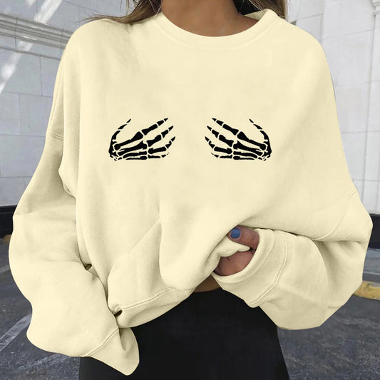 Beige sweatshirt with skeleton design on a person against a tiled wall background