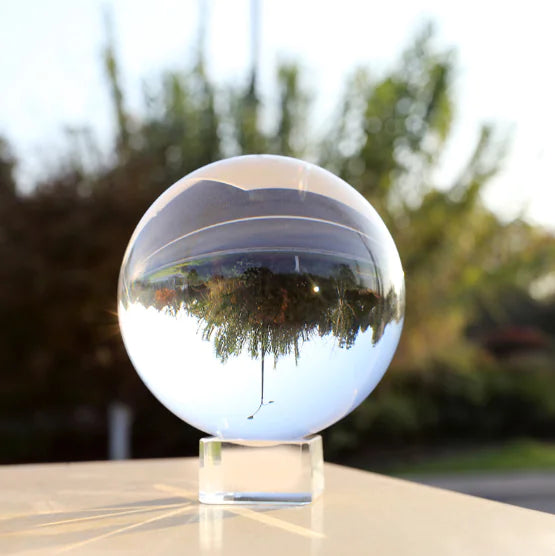 Clear crystal ball reflecting trees on a blurred outdoor background