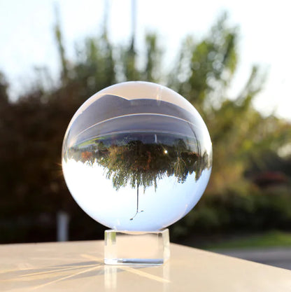 Clear crystal ball reflecting trees on a blurred outdoor background