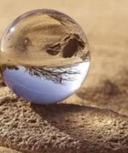 Two crystal balls reflecting different landscapes, one on sand and one on snow.