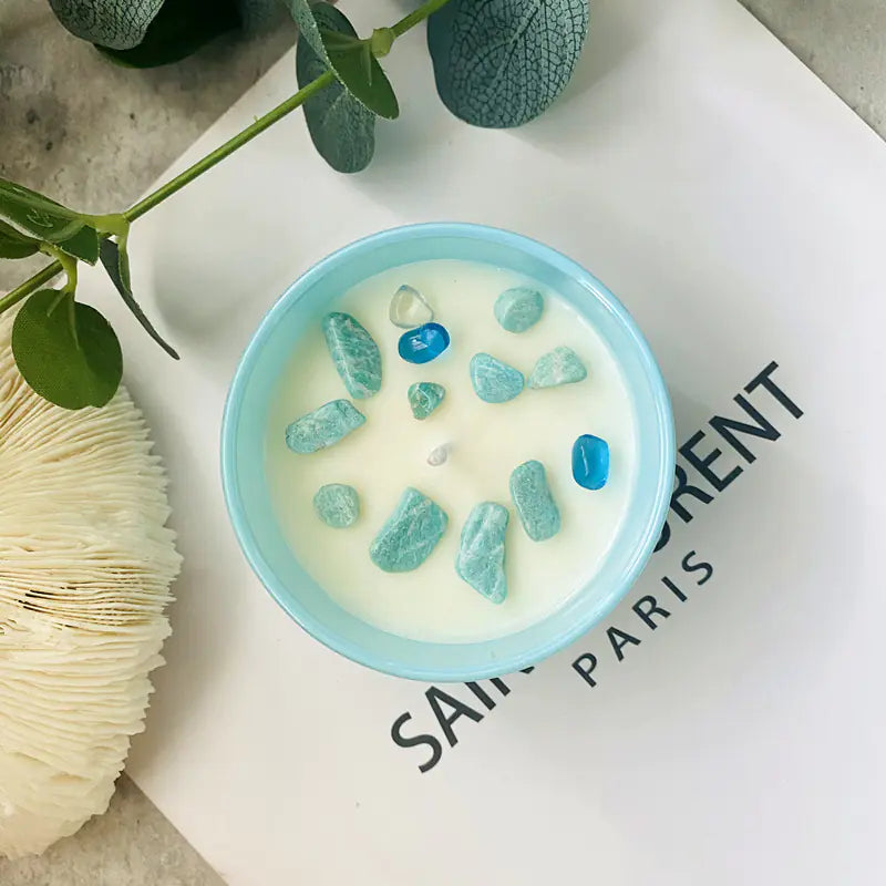 Candle with blue beads in a light blue holder on a newspaper background