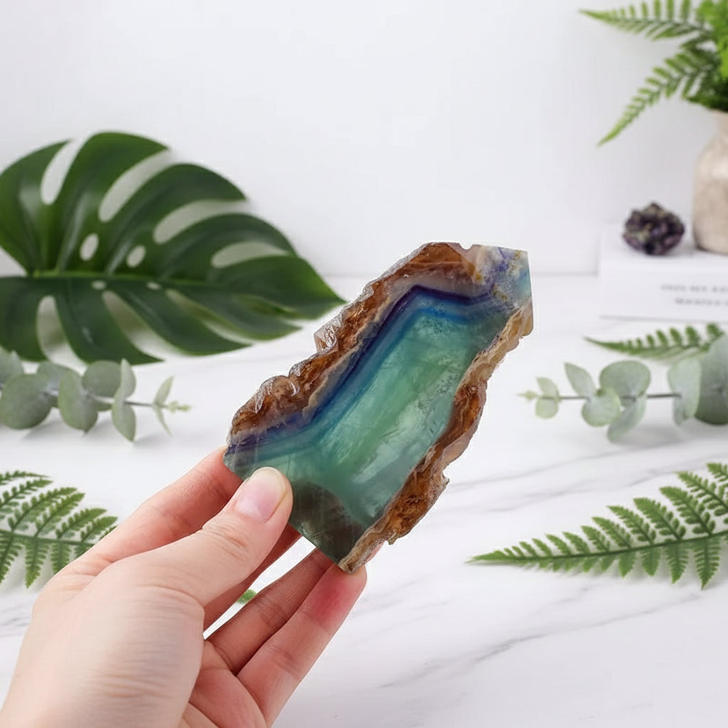 Hand holding a colorful crystal with measurement text on a white background