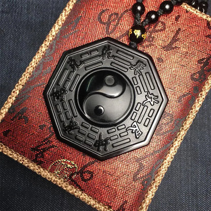 Black hexagonal pendant with yin yang symbol on a red and gold textured background