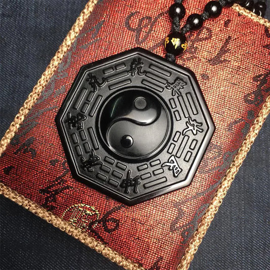 Black hexagonal pendant with yin yang symbol on a red and gold textured background
