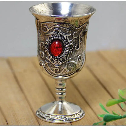 Decorative silver goblet with a red gemstone on a wooden surface