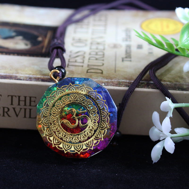 Necklace with a colorful pendant featuring an Om symbol on a dark surface with flowers.
