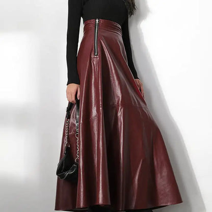 Person wearing a burgundy leather skirt with a black top on a white background