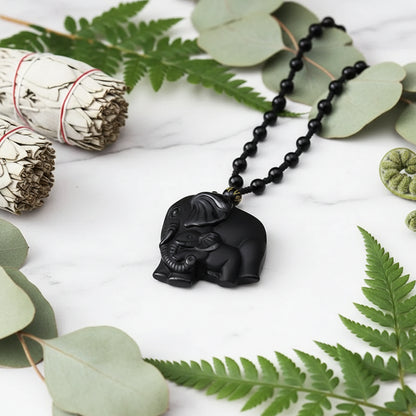 Black elephant pendant with white details on a blurred floral background