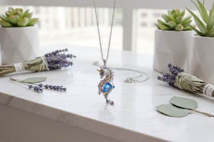 Unicorn-shaped pendant with blue gemstone on a finger