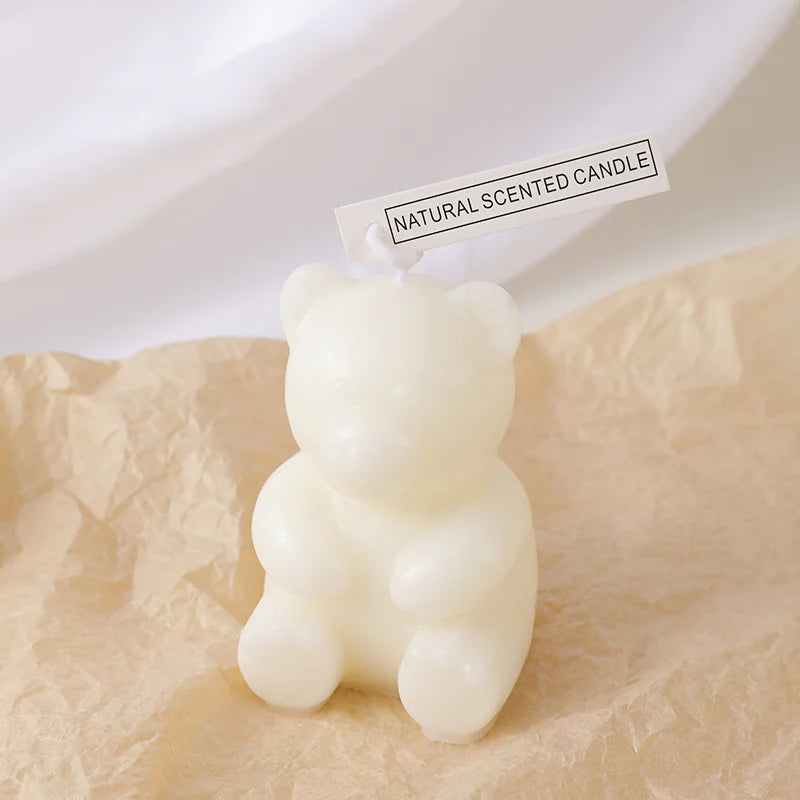 White bear-shaped scented candle on a textured surface with a label indicating it is a natural scented candle.