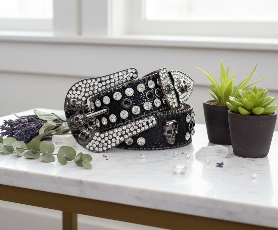 Black belt with silver skull designs and rhinestone embellishments on a white background