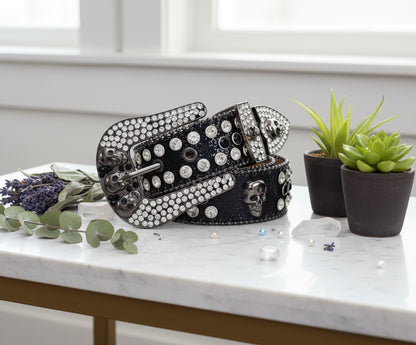 Black belt with silver skull designs and rhinestone embellishments on a white background