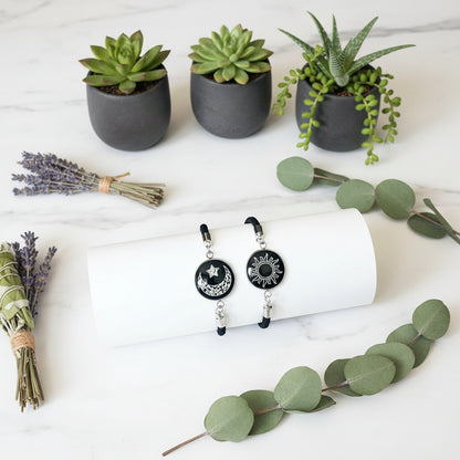Pair of black and white sun and moon keychains on a white surface