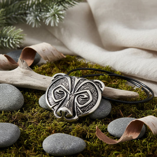 Silver pendant with intricate design on a blue velvet stand