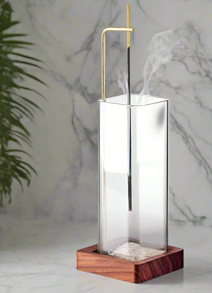Modern incense burner with glass container and wooden base on a white background