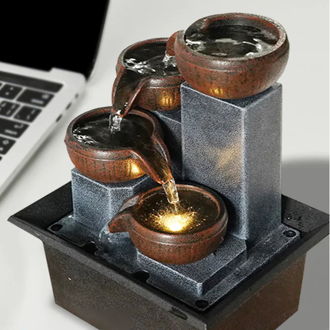 Small decorative fountain on a desk next to a laptop with text indicating stock availability and fast delivery.