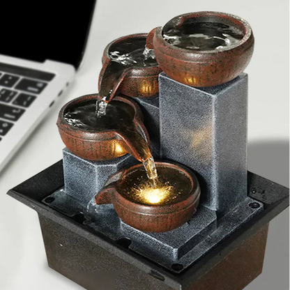 Small decorative fountain on a desk next to a laptop with text indicating stock availability and fast delivery.