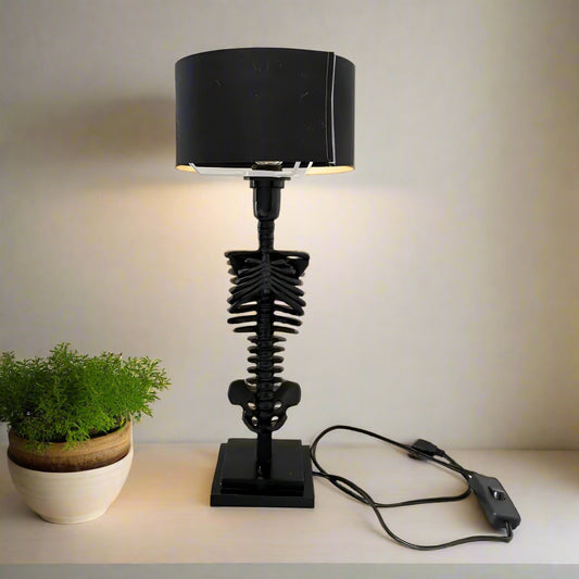 Black skeleton lamp with a black shade on a white surface.