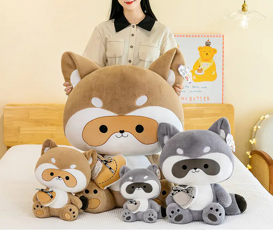 Woman holding a large plush toy with a bear and raccoon design, surrounded by smaller plush toys on a bed.
