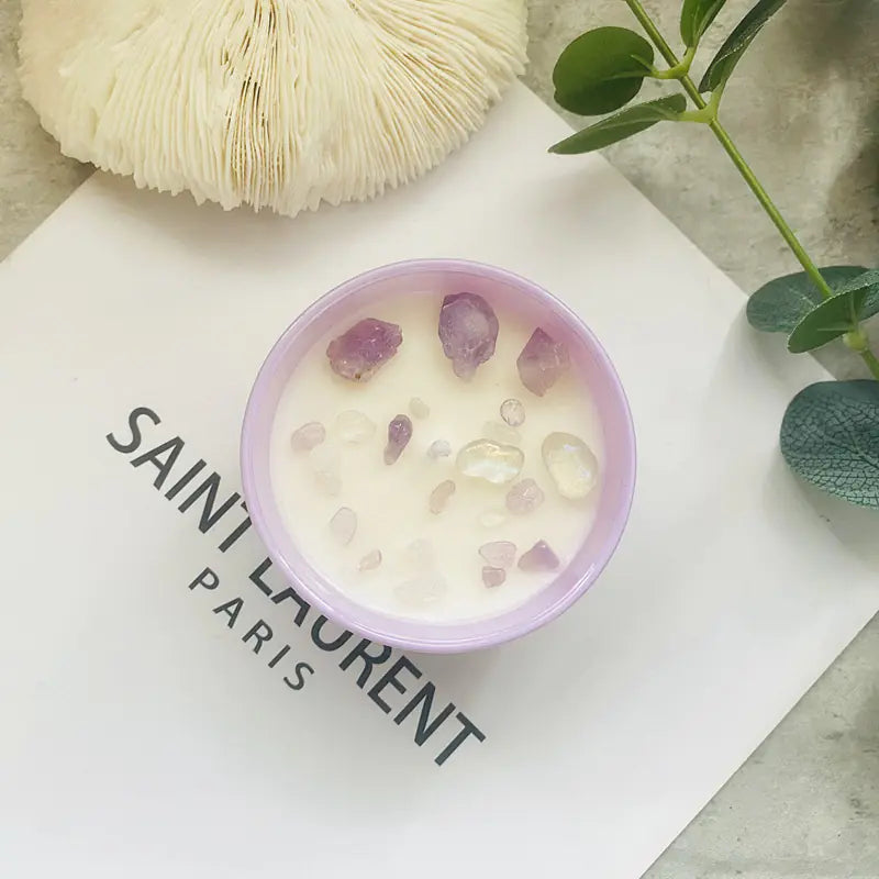 Candle with purple stones in a Saint Laurent container on a branded surface