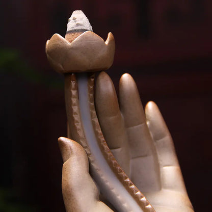 Incense burner shaped like a lotus flower held in a hand with a blurred background