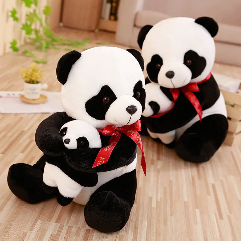 Two panda plush toys with red ribbons on a wooden floor.