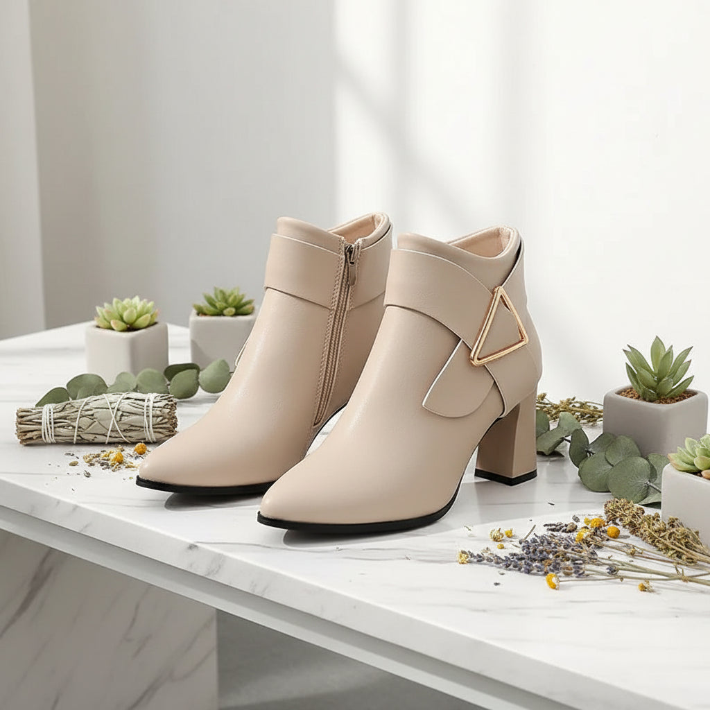 Beige ankle boots with a high heel worn by a person on a city street.